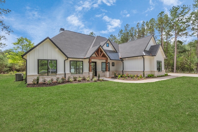 modern farmhouse featuring metal roof, stone siding, board and batten siding, a standing seam roof, and a front yard