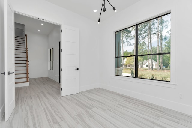 unfurnished room featuring a notable chandelier and light wood-type flooring