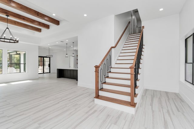 stairway with a notable chandelier, hardwood / wood-style flooring, and beam ceiling