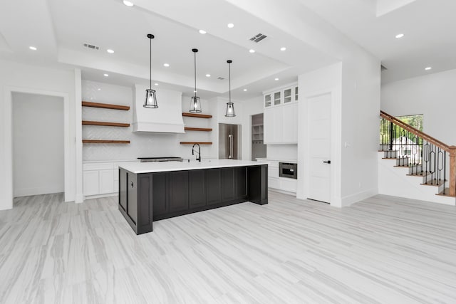 kitchen featuring white cabinets, hanging light fixtures, stainless steel appliances, a spacious island, and light wood-type flooring