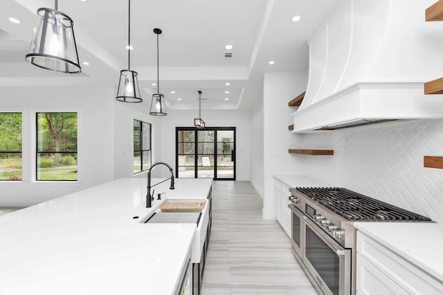 kitchen featuring pendant lighting, range with two ovens, plenty of natural light, and premium range hood