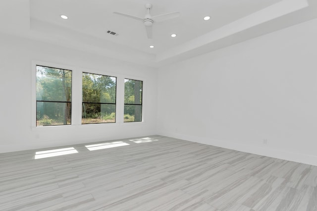 spare room featuring ceiling fan, a raised ceiling, and light hardwood / wood-style floors