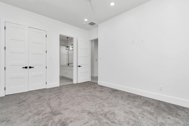 unfurnished bedroom featuring carpet floors, a closet, and ensuite bathroom