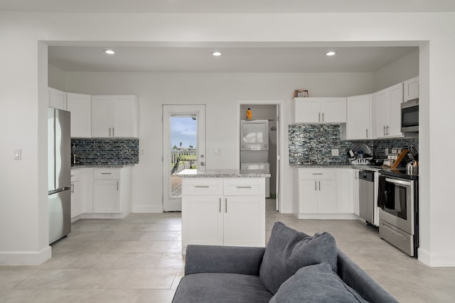 kitchen featuring decorative backsplash, white cabinetry, stainless steel appliances, and light stone counters