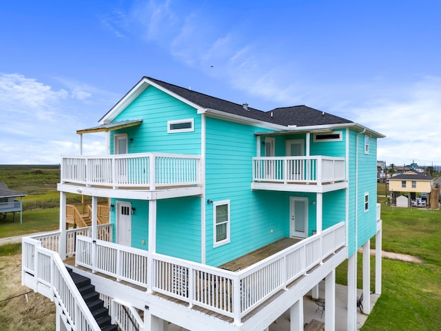 rear view of house with a yard and a balcony