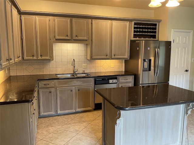 kitchen featuring sink, dishwasher, dark stone countertops, stainless steel fridge, and light tile patterned flooring