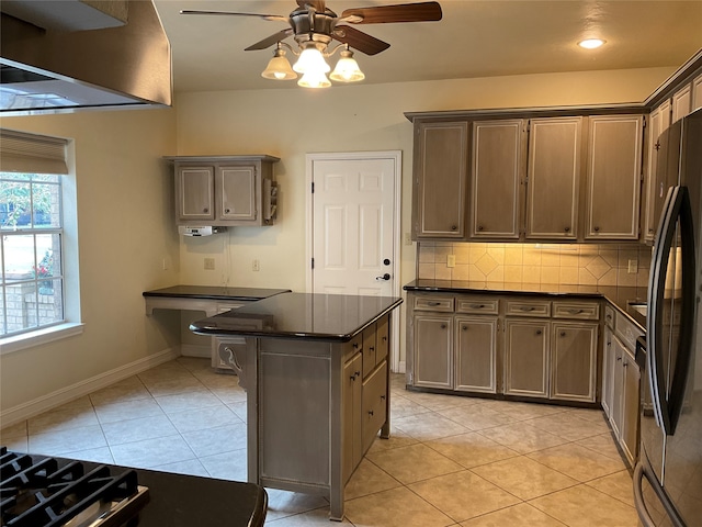 kitchen featuring decorative backsplash, stainless steel fridge, ceiling fan, a center island, and light tile patterned flooring