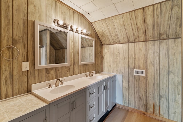 bathroom with wood walls, lofted ceiling, and vanity