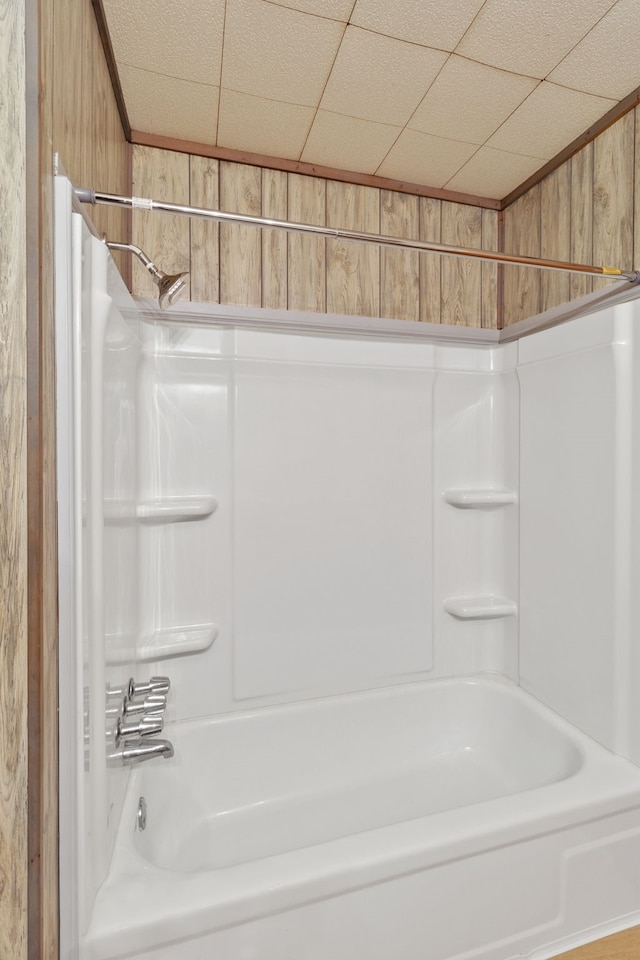 bathroom featuring wooden walls and shower / washtub combination