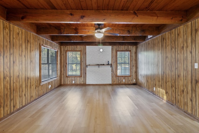 unfurnished living room with light hardwood / wood-style flooring, a wealth of natural light, beamed ceiling, and wooden walls