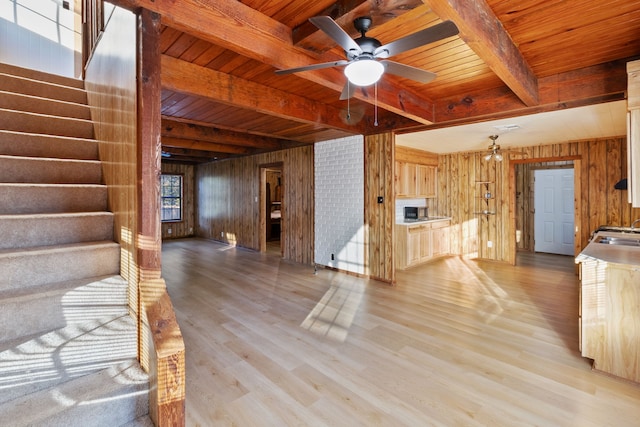 unfurnished living room featuring wood walls, light hardwood / wood-style floors, beamed ceiling, and wooden ceiling