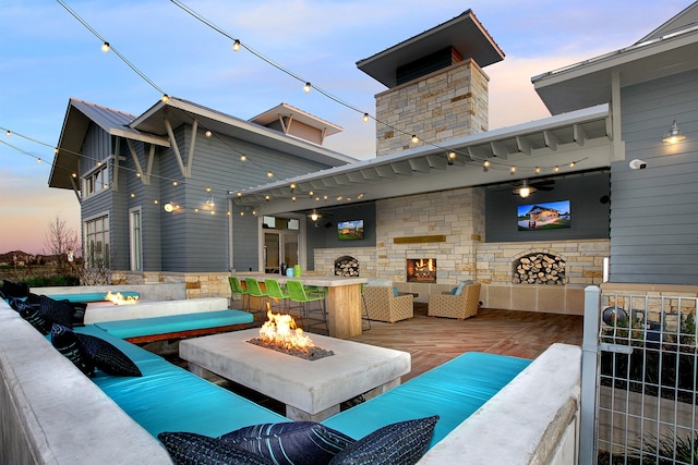 patio terrace at dusk featuring an outdoor living space with a fire pit and a wooden deck