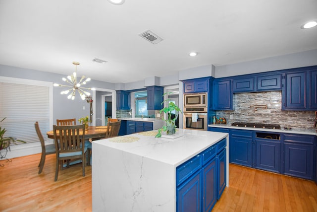 kitchen with light hardwood / wood-style flooring, backsplash, a center island, blue cabinetry, and appliances with stainless steel finishes