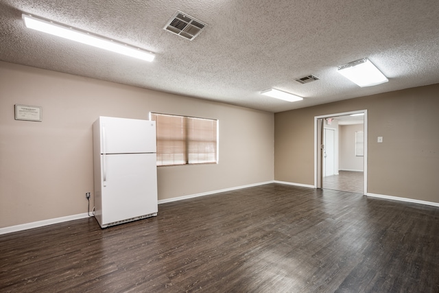 spare room with a textured ceiling and dark hardwood / wood-style floors