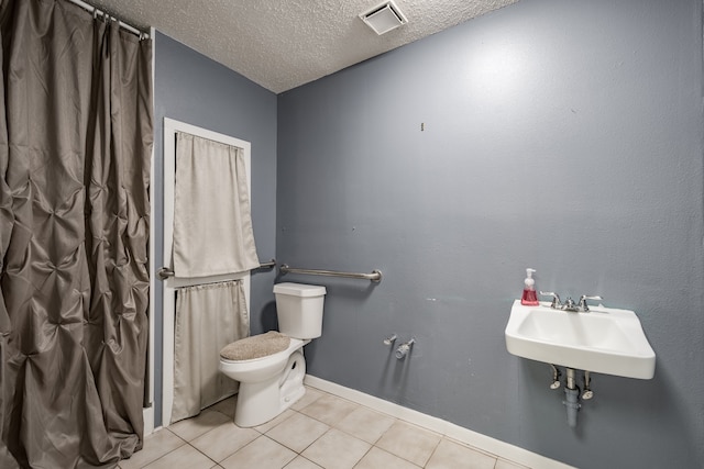 bathroom with tile patterned floors, toilet, sink, and a textured ceiling