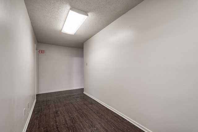 empty room with dark hardwood / wood-style flooring and a textured ceiling