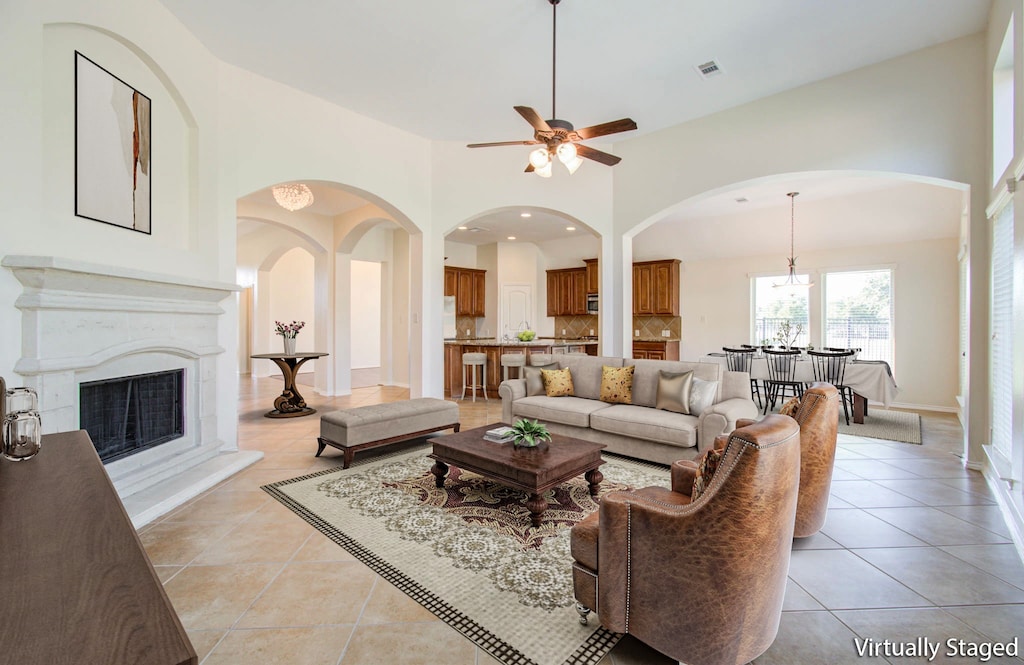 living room with ceiling fan, light tile patterned flooring, and a high ceiling