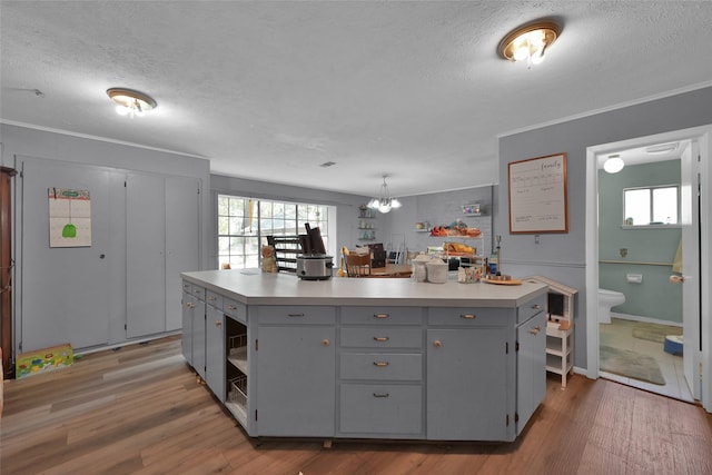 kitchen with pendant lighting, hardwood / wood-style floors, gray cabinetry, and a kitchen island