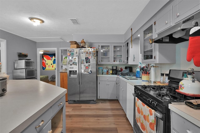 kitchen featuring sink, light hardwood / wood-style flooring, gray cabinets, appliances with stainless steel finishes, and a textured ceiling