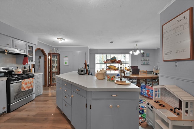 kitchen with gray cabinets, gas stove, a kitchen island, and pendant lighting