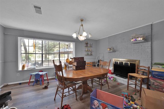 dining area with a notable chandelier, hardwood / wood-style flooring, and a fireplace