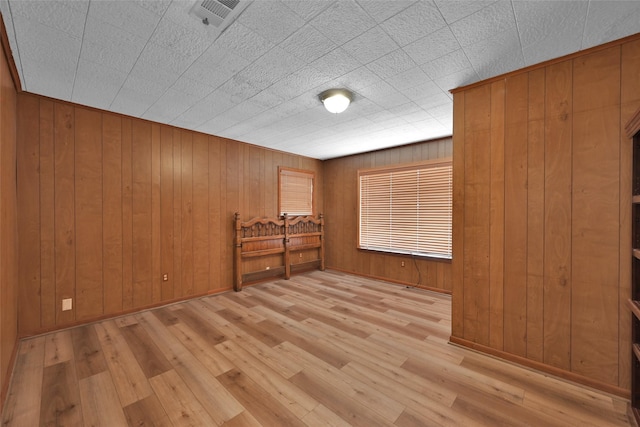 spare room featuring light hardwood / wood-style floors and wood walls