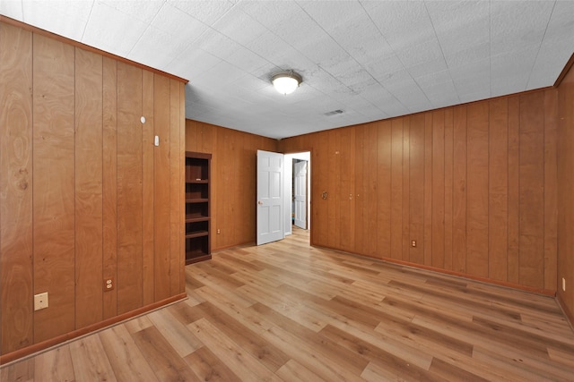 unfurnished bedroom with wooden walls and light hardwood / wood-style flooring