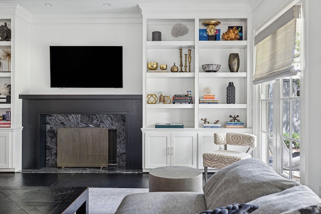 living room featuring ornamental molding, a fireplace, and built in features