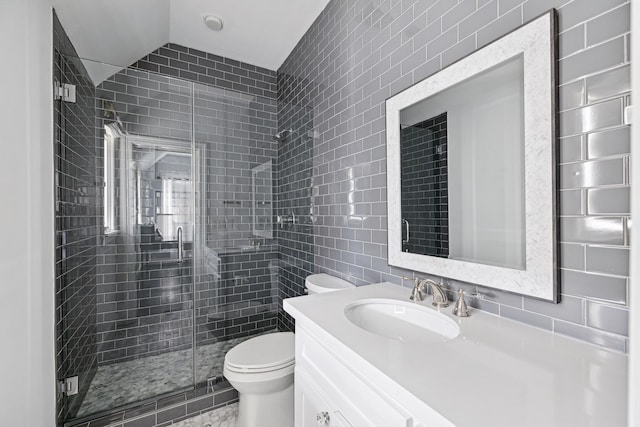 bathroom featuring vaulted ceiling, tile walls, vanity, a shower with shower door, and toilet