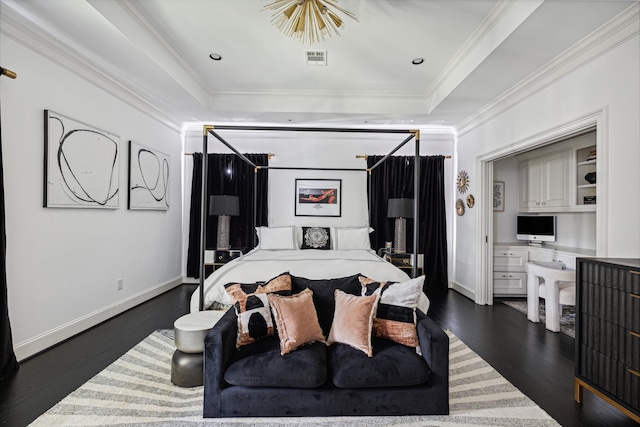 bedroom featuring ornamental molding, dark hardwood / wood-style floors, built in desk, and a tray ceiling