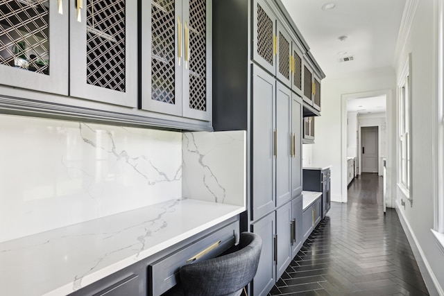 kitchen featuring gray cabinetry, light stone countertops, and dark parquet floors