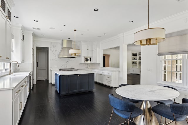 kitchen with hanging light fixtures, tasteful backsplash, extractor fan, white cabinets, and a kitchen island