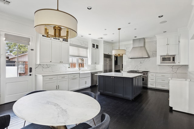 kitchen with white cabinetry, extractor fan, built in appliances, and hanging light fixtures