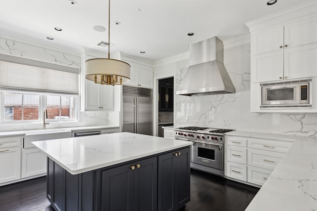 kitchen with sink, built in appliances, ventilation hood, white cabinets, and decorative light fixtures