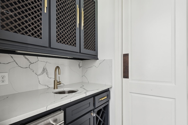 bar with sink, gray cabinetry, dishwasher, light stone countertops, and decorative backsplash