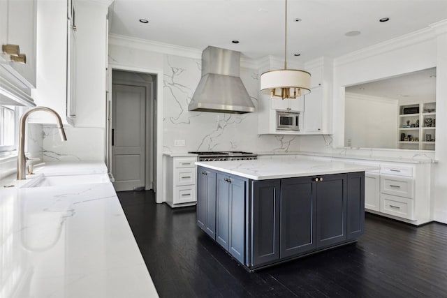 kitchen featuring sink, hanging light fixtures, stainless steel microwave, light stone countertops, and island exhaust hood