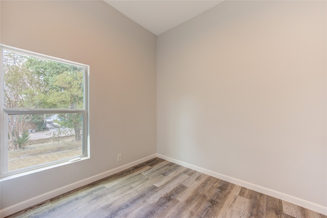 spare room featuring vaulted ceiling, light hardwood / wood-style flooring, and a wealth of natural light