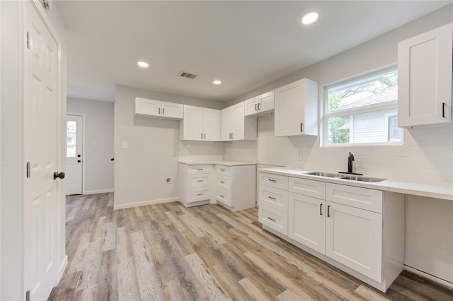 kitchen featuring a healthy amount of sunlight, white cabinetry, sink, and light hardwood / wood-style flooring