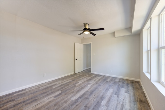 empty room with a textured ceiling, light wood-type flooring, and ceiling fan