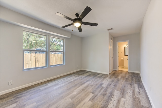 unfurnished bedroom featuring ceiling fan, a textured ceiling, light hardwood / wood-style flooring, and ensuite bathroom