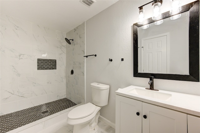 bathroom with a tile shower, vanity, and toilet