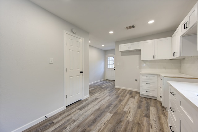 kitchen featuring white cabinetry, wood-type flooring, and backsplash