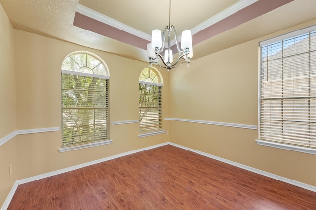 empty room with an inviting chandelier, hardwood / wood-style flooring, and ornamental molding