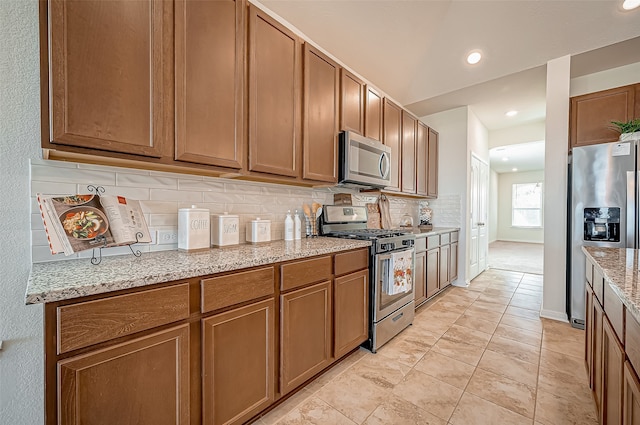 kitchen featuring light stone countertops, backsplash, and appliances with stainless steel finishes