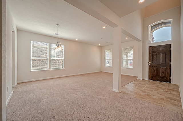 foyer featuring a notable chandelier, light colored carpet, and plenty of natural light