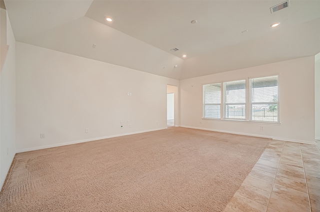 carpeted spare room featuring vaulted ceiling