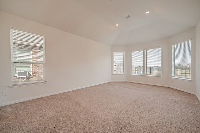 empty room with light colored carpet and vaulted ceiling