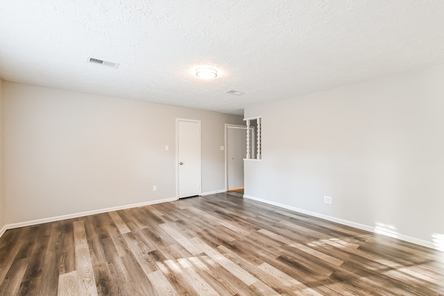 spare room with a textured ceiling and wood-type flooring