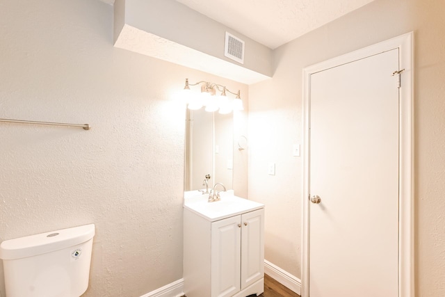 bathroom featuring vanity, visible vents, toilet, and wood finished floors