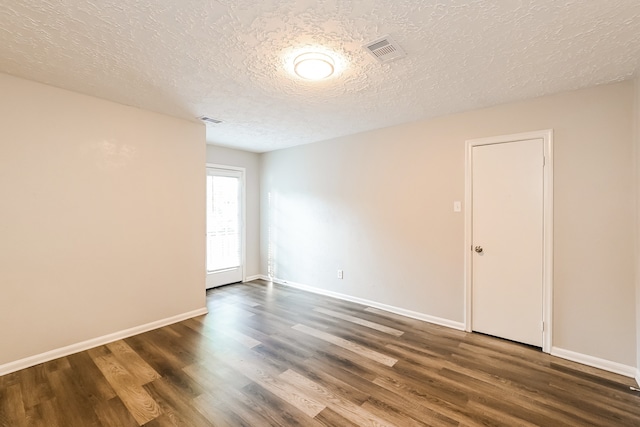 unfurnished room featuring a textured ceiling and dark hardwood / wood-style floors